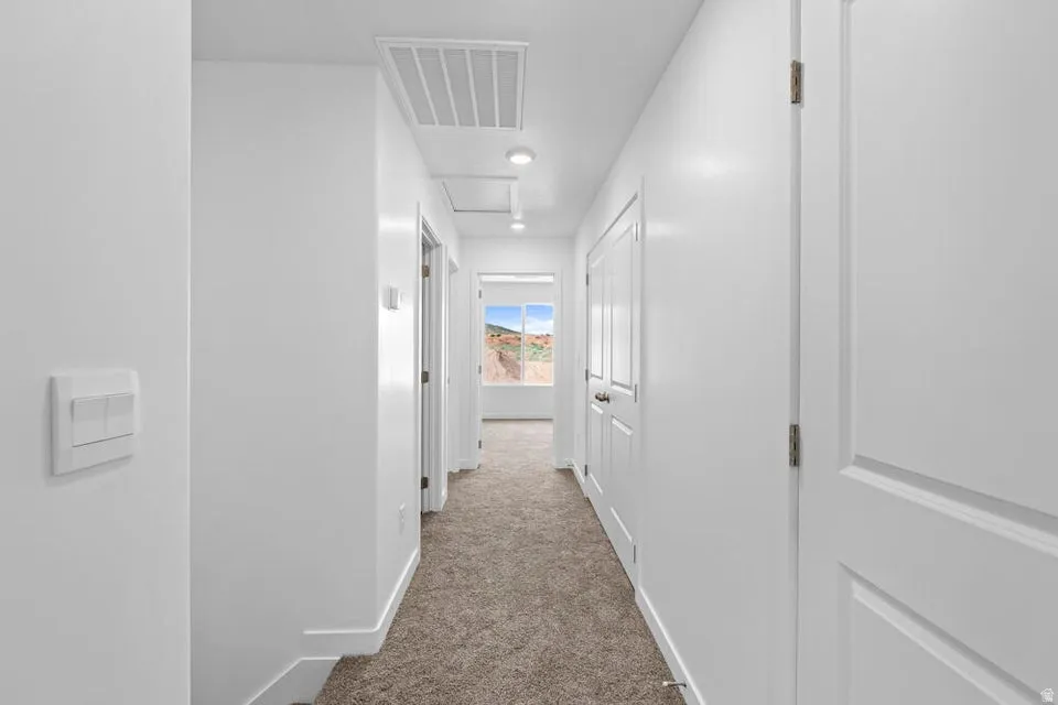 Hallway with neutral tone carpeting and white painted walls