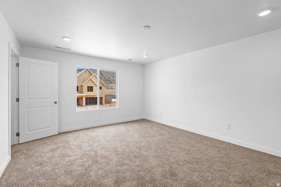 Spacious room featuring new carpeting, recessed lighting, white trim, a single window, and a paneled door