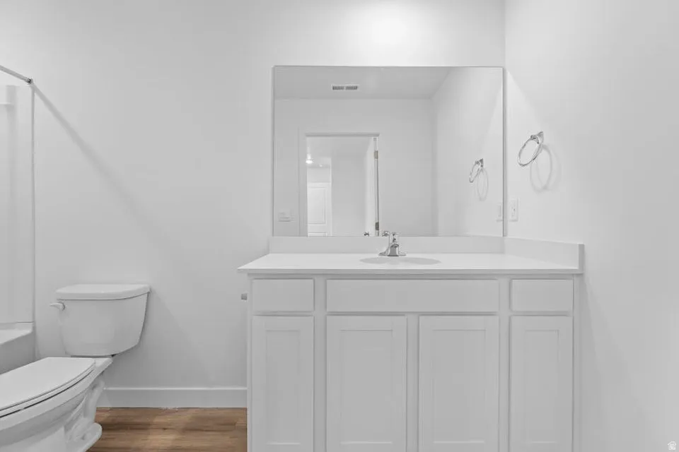 Bathroom featuring a single-sink vanity with white cabinetry, a light-toned countertop, and a large wall-mounted mirror