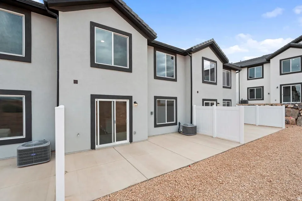 Rear exterior featuring a concrete patio, vinyl privacy fencing, and a gravel border