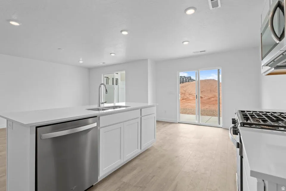 Kitchen island featuring a stainless steel dishwasher, undermount sink, and quartz-finish countertop