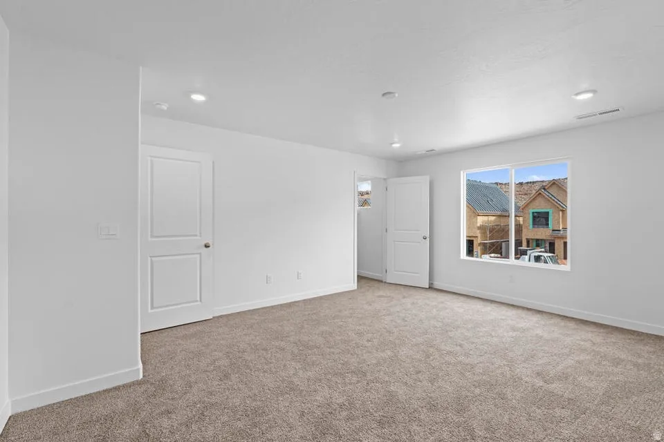 Carpeted room with recessed lighting and white baseboards