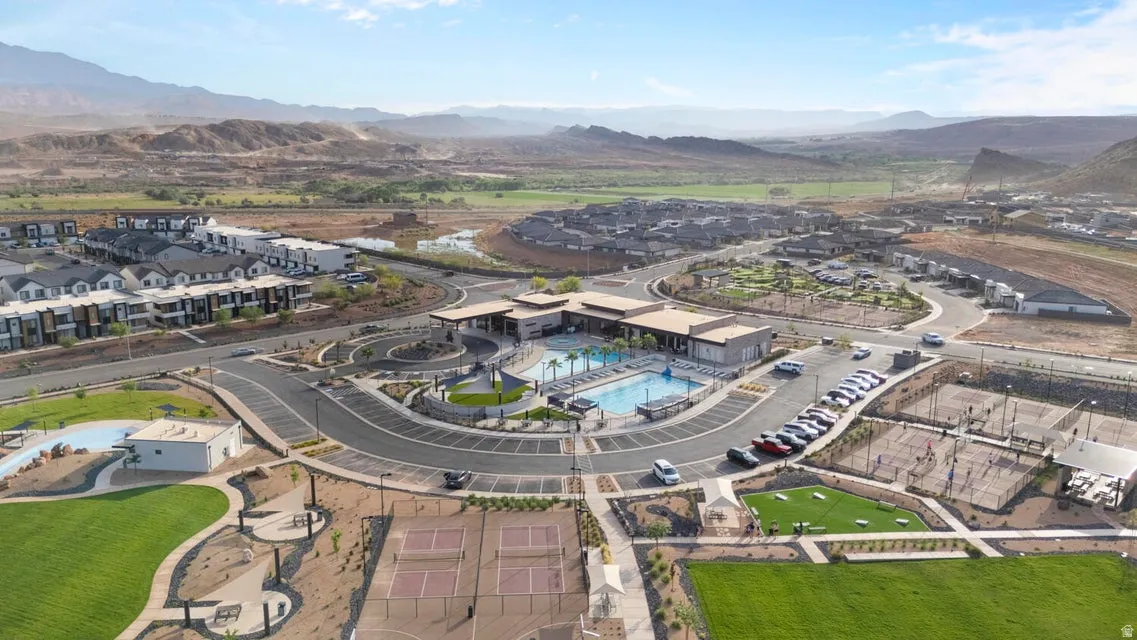 Community hub featuring a central building with an outdoor swimming pool, multiple tennis courts, and expansive green spaces