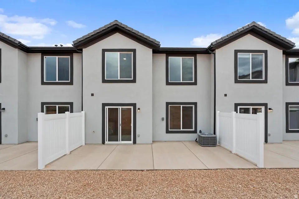 Modern stucco exterior with dark trim and a concrete patio