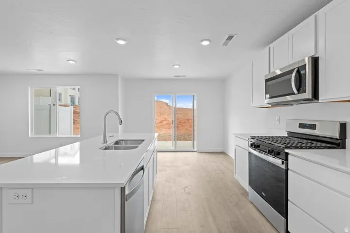 Modern kitchen featuring a large island with a double basin sink and gooseneck faucet