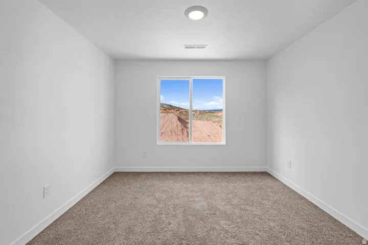 Room featuring a large window, neutral carpeting, white walls, white trim, and a ceiling-mounted light fixture