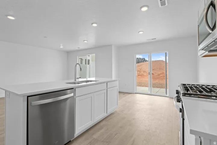 Kitchen island featuring a stainless steel dishwasher, undermount sink, and quartz-finish countertop
