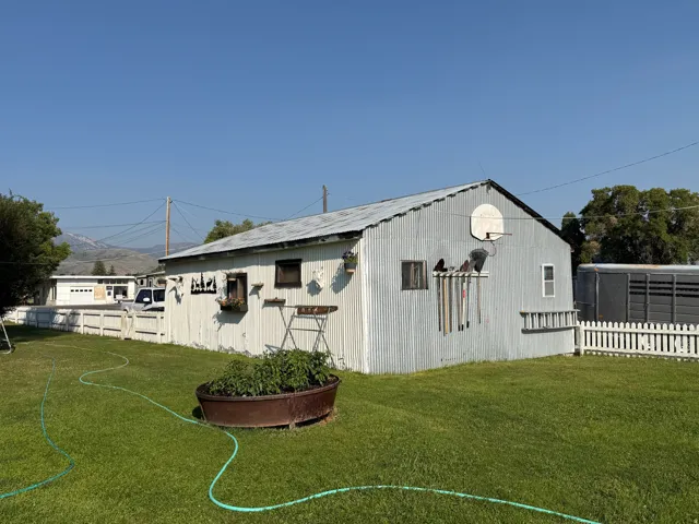 Expansive green lawn with a large utility building / detached garage featuring corrugated metal siding and a pitched roof