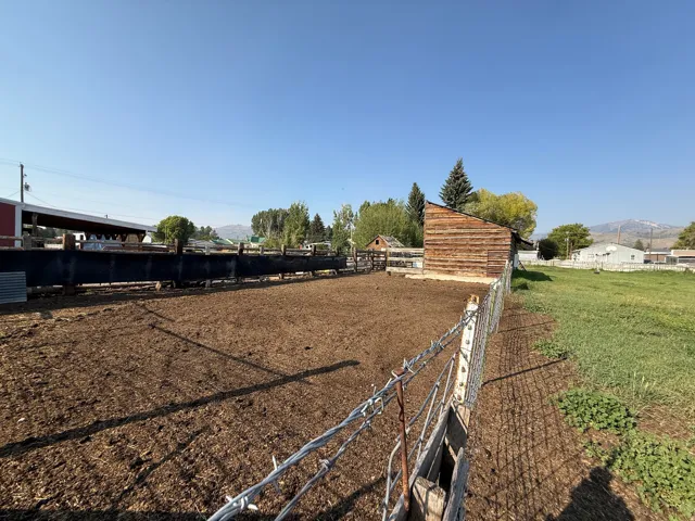 Expansive fenced paddock area featuring a log-style outbuilding and additional covered structure