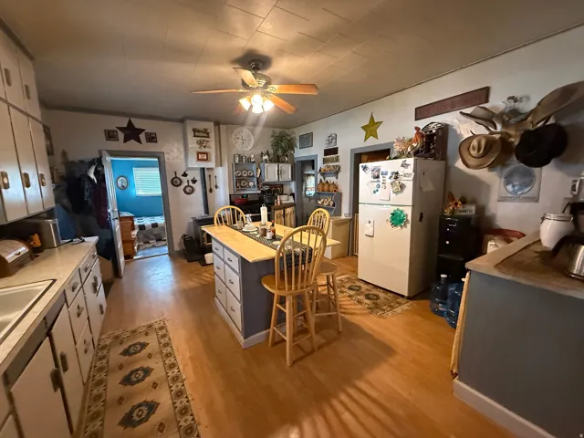 Kitchen featuring a central island with integrated seating, wood-finish flooring, white cabinetry, a built-in sink, and a ceiling fan