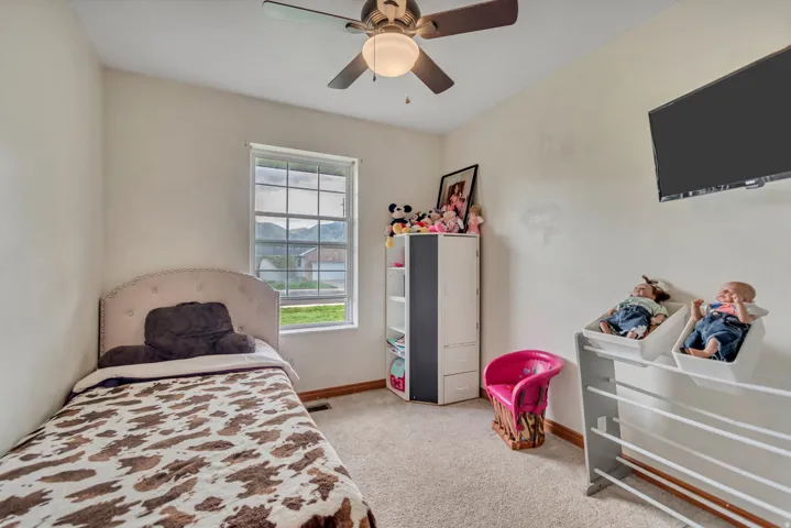 Carpeted room featuring a ceiling fan with integrated lighting, a window with a mountain backdrop, and a mounted wall display