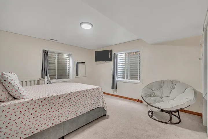 Carpeted room featuring light-toned walls, a flush-mount ceiling light, and a window with horizontal blinds