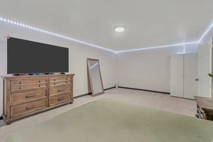 Spacious room featuring light-colored carpeting, white walls, and a ceiling-mounted light fixture