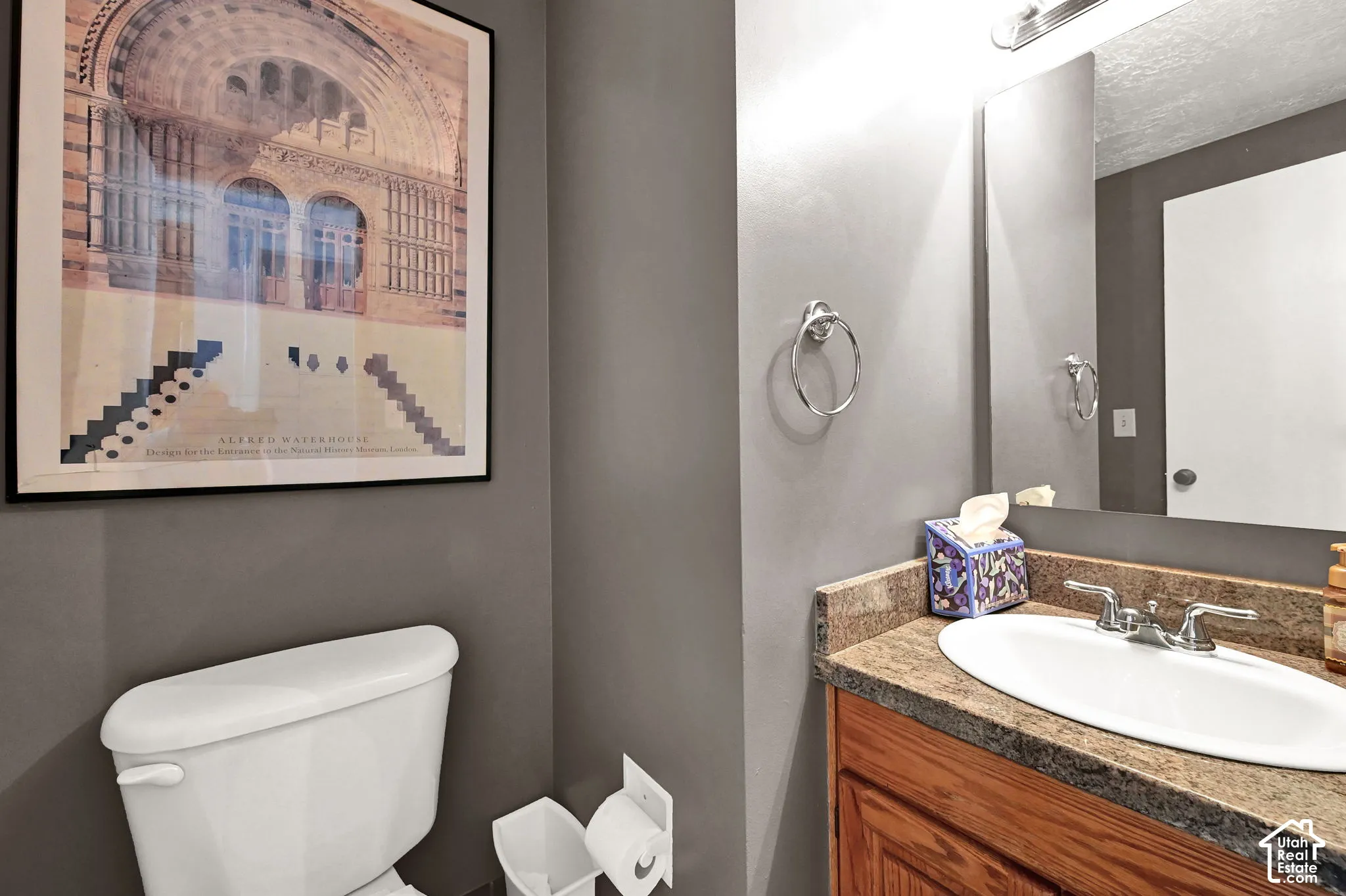 Sophisticated powder room featuring charcoal gray walls, a wood-finish vanity with an undermount ceramic sink, and chrome fixtures