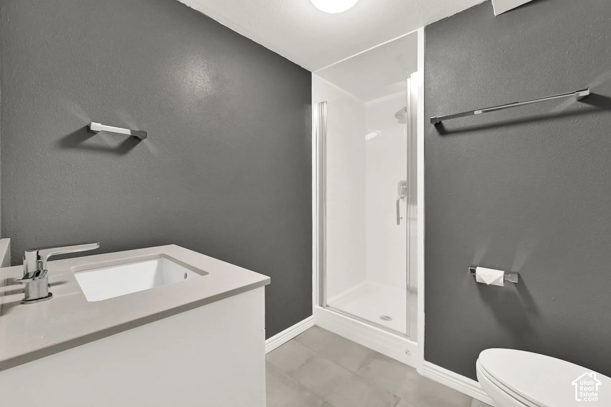 Bathroom featuring a white vanity with an integrated sink, polished chrome faucet, and a glass-enclosed shower