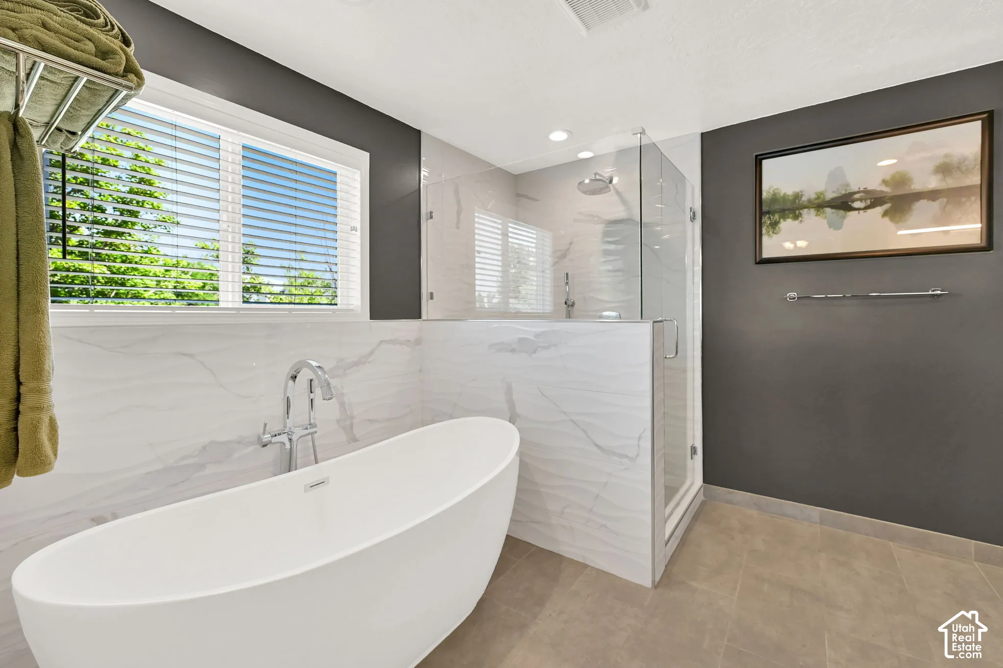 Spa-inspired primary bathroom featuring a freestanding white soaking tub and a frameless glass-enclosed walk-in shower