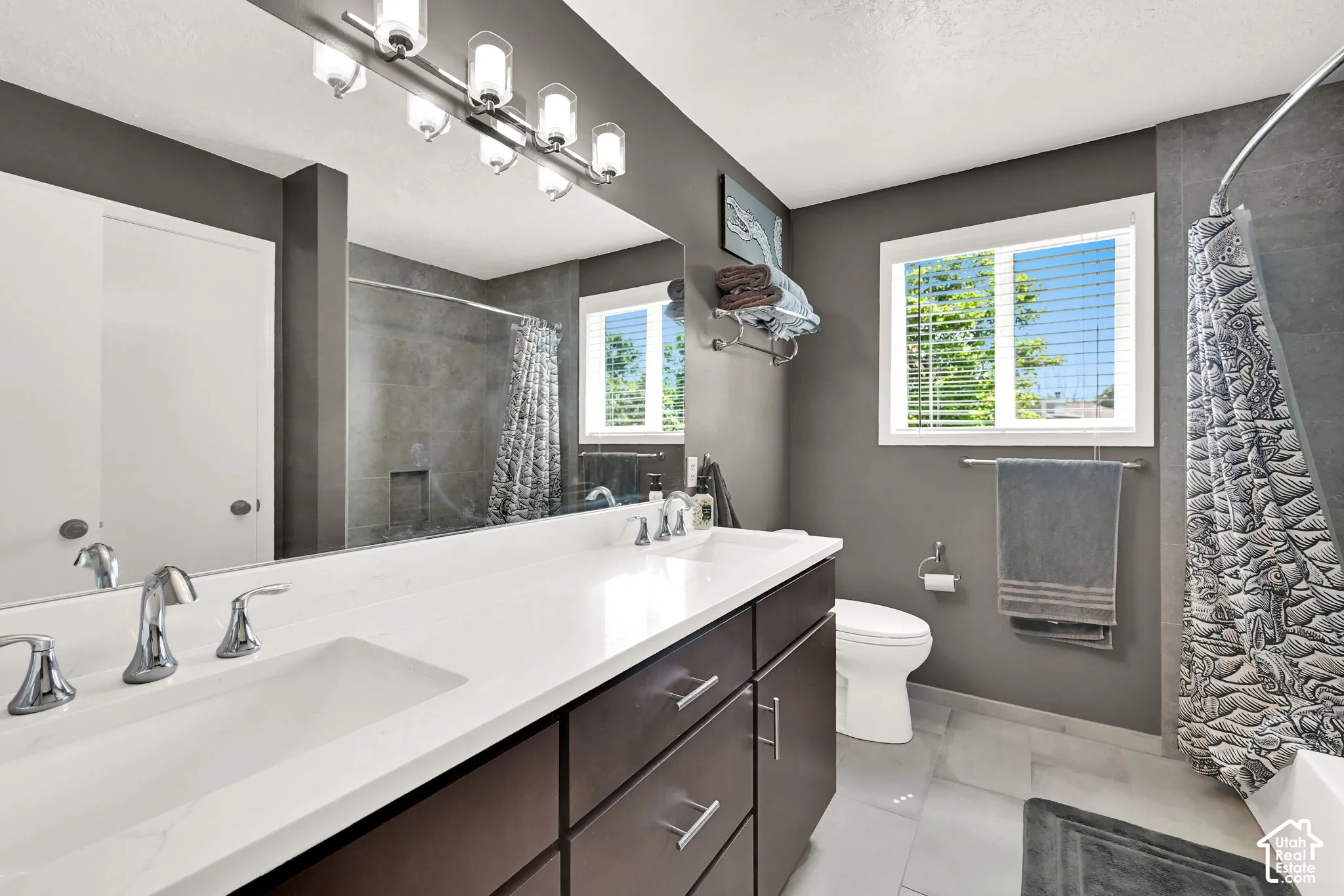 Guest bathroom featuring a dual-sink vanity with a quartz countertop, chrome fixtures, and dark wood-finish cabinetry