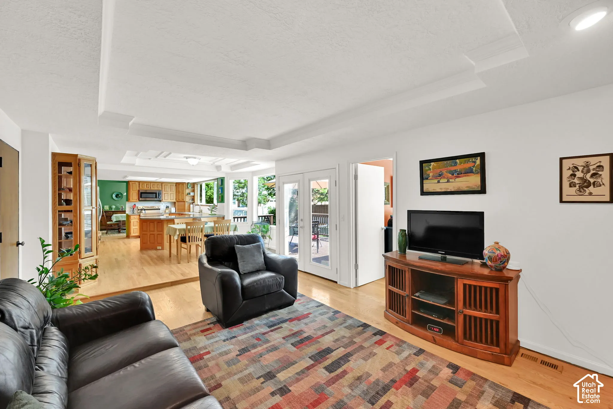 Living area featuring light wood-finish flooring and a multi-tiered tray ceiling