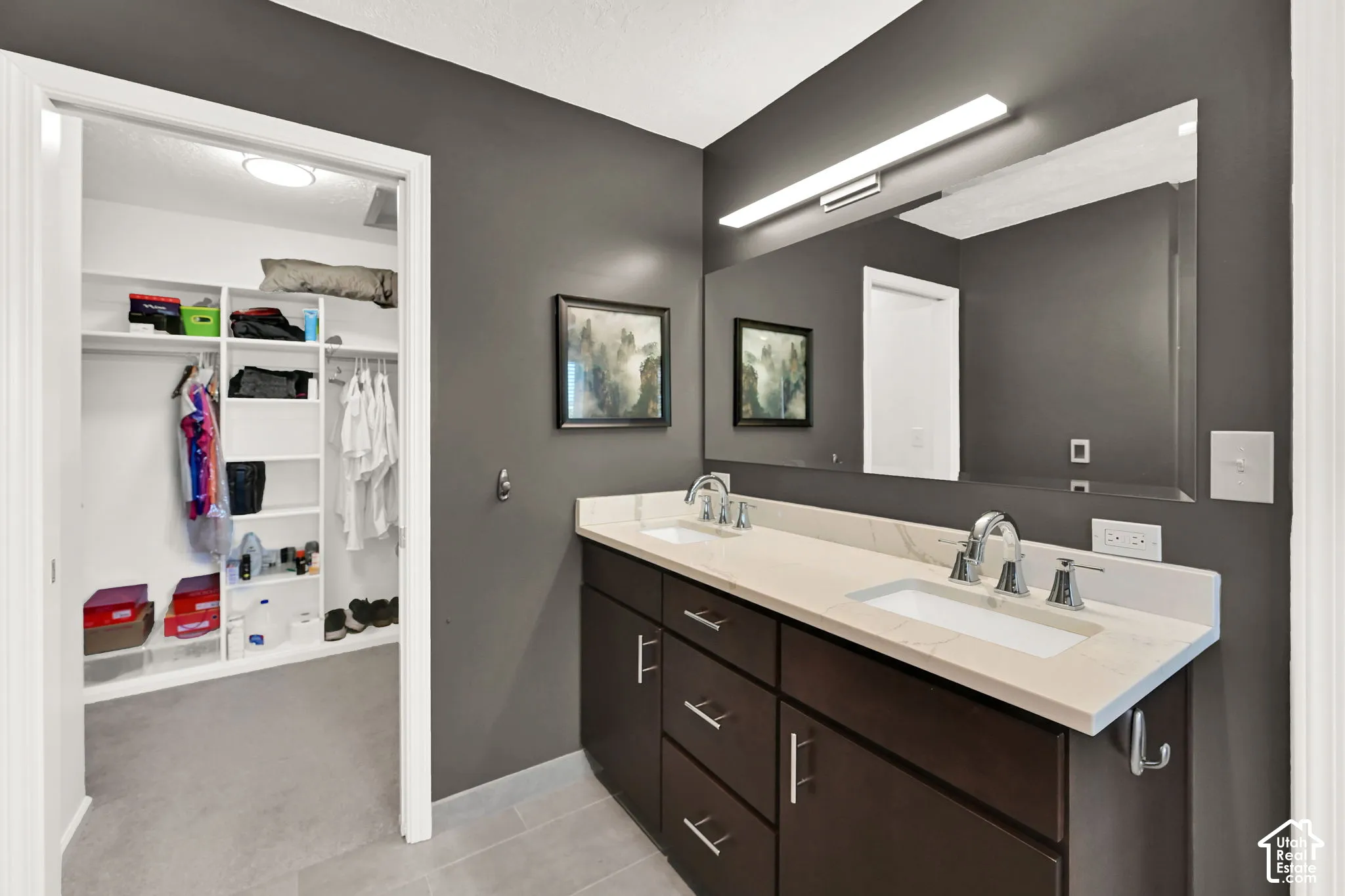 Bathroom vanity featuring dual sinks, a quartz countertop, and dark wood cabinetry with chrome hardware