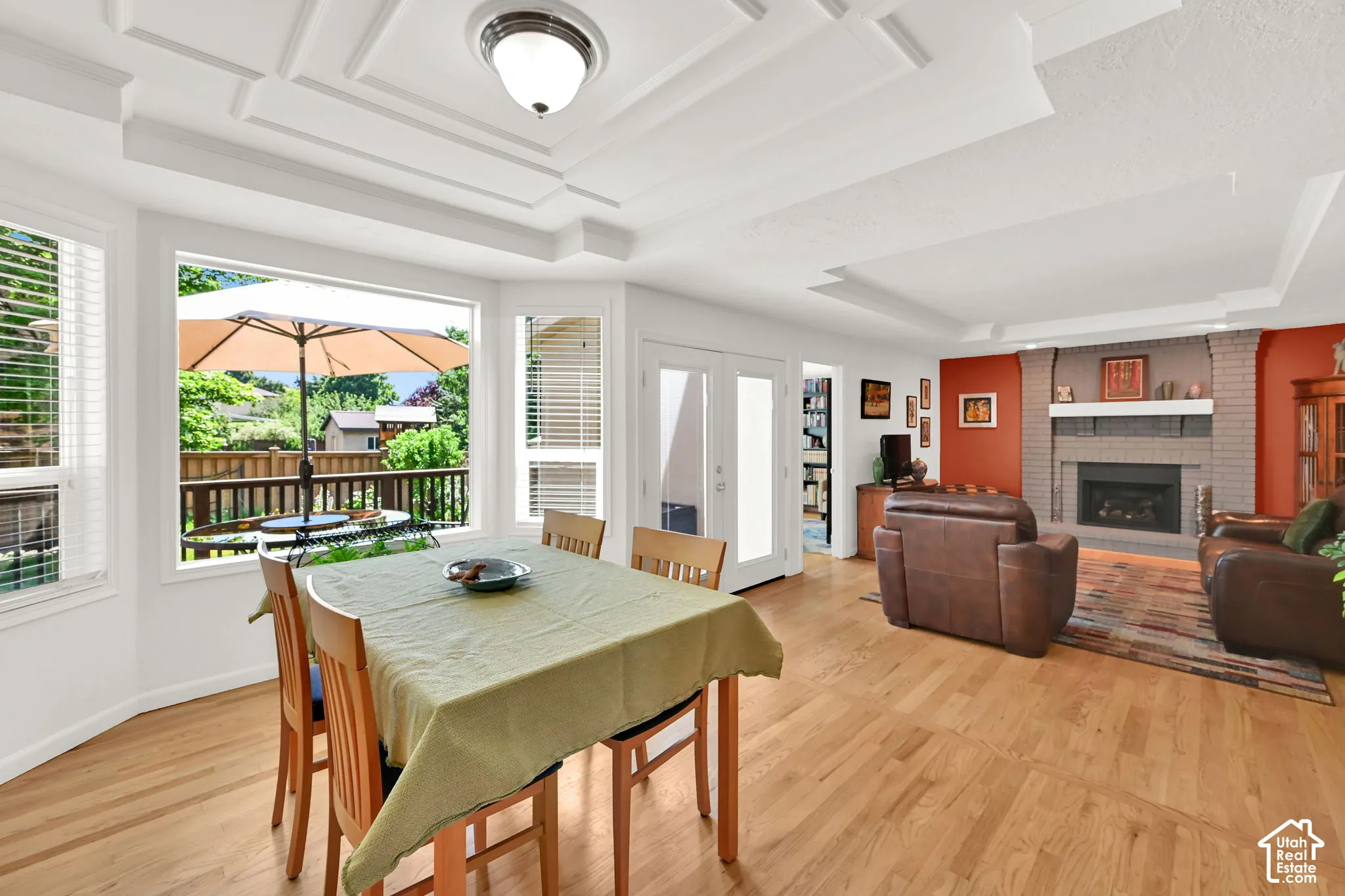 Expansive living area featuring wood-finish flooring, a tray ceiling, and a brick fireplace