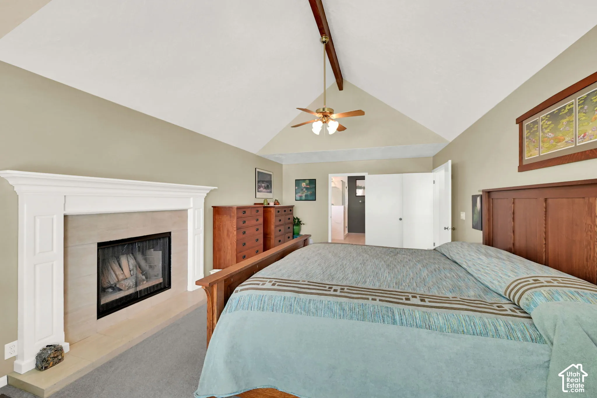 Spacious primary bedroom suite featuring a vaulted ceiling with ceiling fan, and an ensuite fireplace with white surround