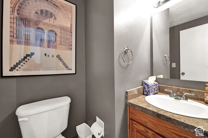 Sophisticated powder room featuring charcoal gray walls, a wood-finish vanity with an undermount ceramic sink, and chrome fixtures
