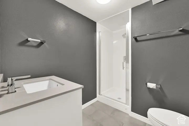 Bathroom featuring a white vanity with an integrated sink, polished chrome faucet, and a glass-enclosed shower