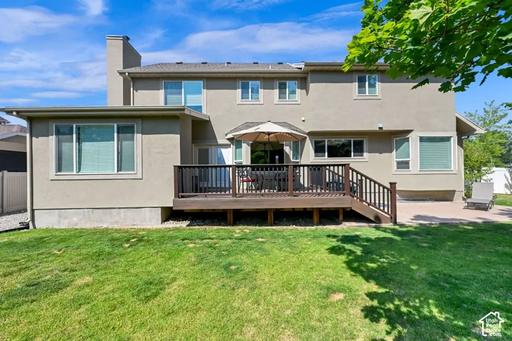 Rear exterior featuring a two-story stucco facade and a spacious wood-finish deck with railings