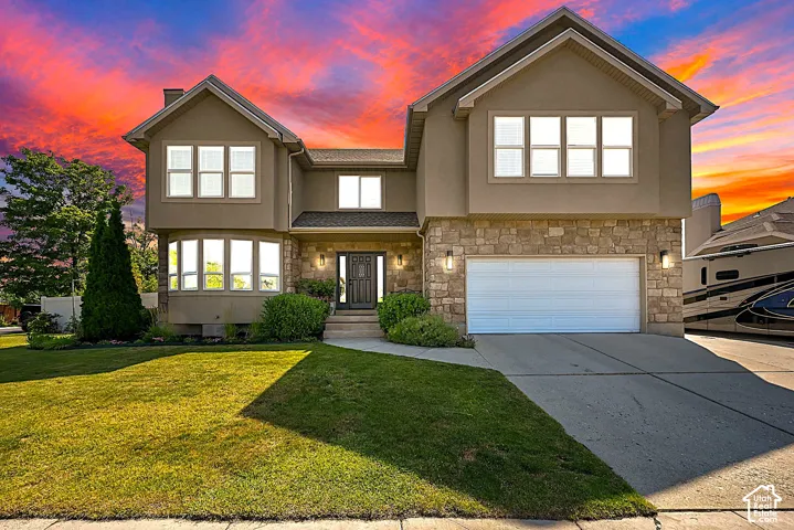 Two-story residence featuring a stone and stucco exterior, an attached two-car garage, and a concrete driveway