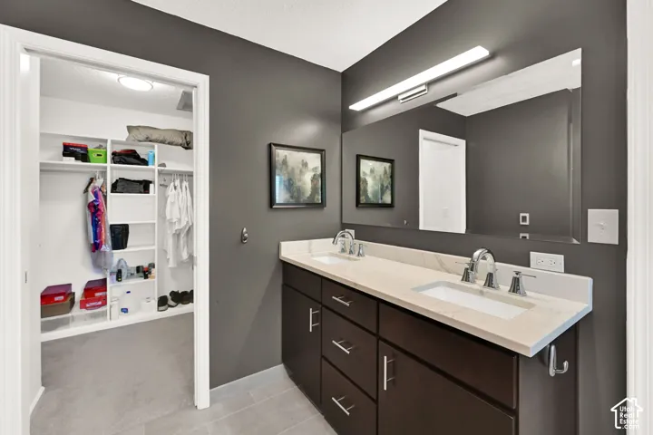 Bathroom vanity featuring dual sinks, a quartz countertop, and dark wood cabinetry with chrome hardware