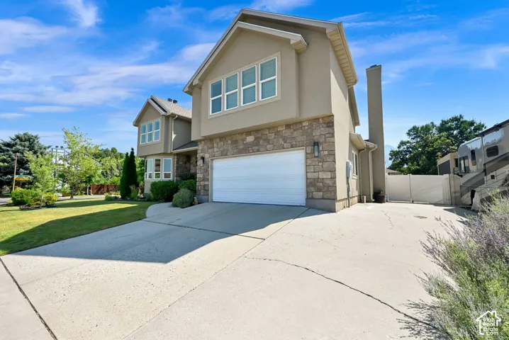 Striking two-story home featuring a clean, modern exterior with stone and siding accents, expansive two-car garage with white overhead door, and RV Parking