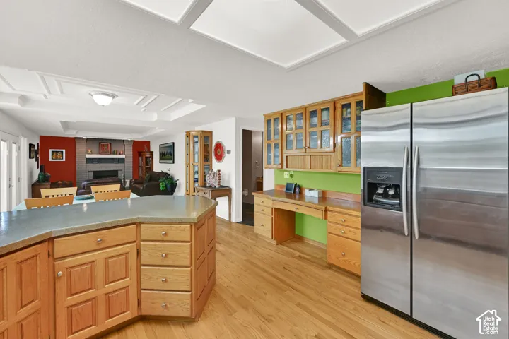 Kitchen featuring a stainless steel side-by-side refrigerator, extensive wood cabinetry, and a built-in desk area
