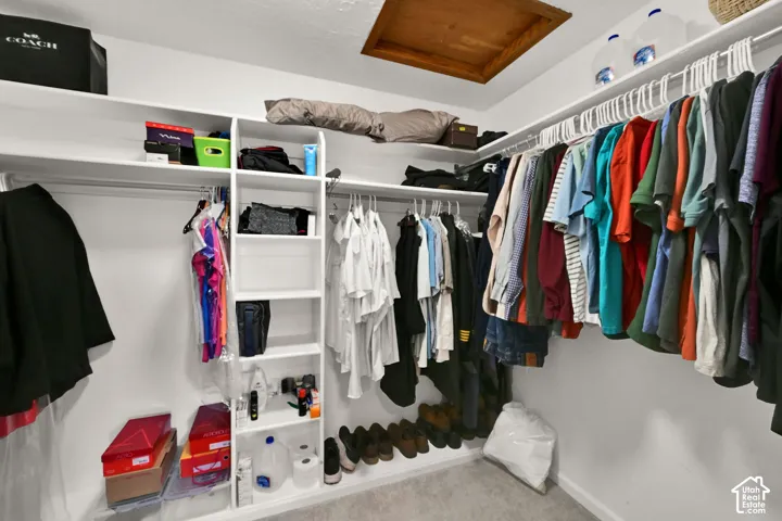 Spacious walk-in closet featuring extensive built-in shelving, multiple clothing rods with organized garment storage, and cubbies for accessories and personal items.