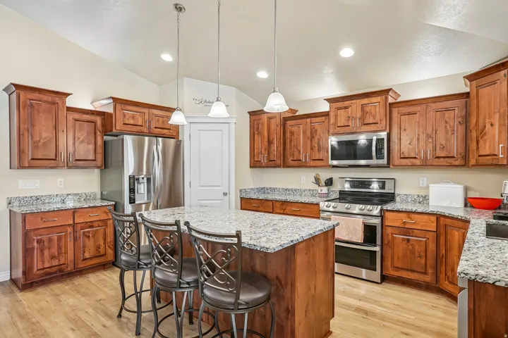 Gourmet kitchen featuring rich wood cabinetry, granite countertops, stainless steel appliances, and a spacious island with seating
