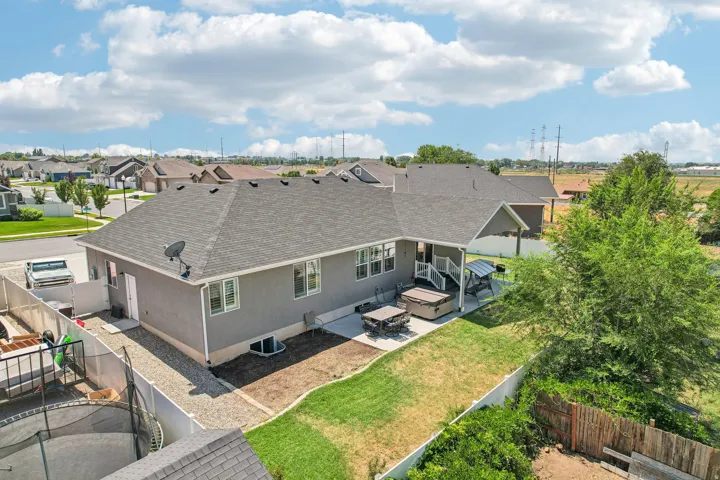 Expansive rear elevation showcasing a contemporary single-story residence with a charcoal asphalt shingle roof, vinyl siding exterior, and multiple casement windows