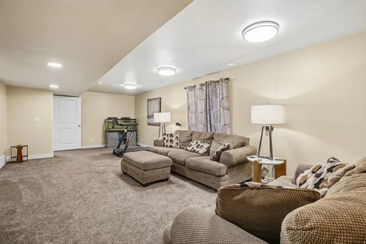 Spacious carpeted room featuring recessed lighting and flush-mount fixtures, light-toned wall paint, and a two-panel interior door