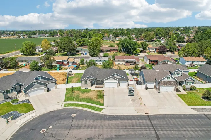 Aerial view of this contemporary home showcasing a spacious driveway with three-car garage, crisp architectural lines with mixed exterior finishes, and manicured landscaping