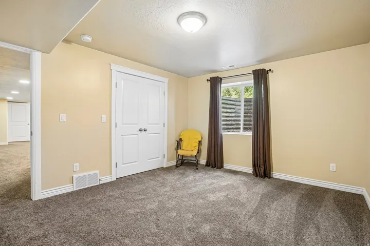 Spacious bedroom with neutral wall finish, plush carpeting, and abundant natural light from shuttered windows