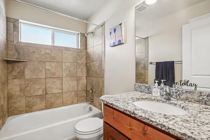 Spa-inspired bathroom featuring a granite-topped double vanity with wood cabinetry, a walk-in shower with tile surround and glass enclosure, and a soaking tub