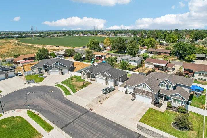 Aerial view showcasing a newly constructed residential community featuring modern single-family homes with contemporary architectural design, dark composition roofing, and manicured landscaping