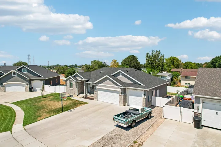 Charming residential street featuring multiple single-family homes with gray and tan exterior finishes, white trim accents, and dark asphalt roofing