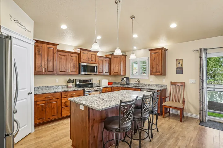 Kitchen featuring a central island with counter seating, granite countertops, wood-finish flooring, recessed lighting, and a stainless steel appliance suite