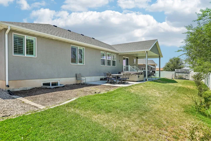 Rear exterior featuring a covered patio, stucco siding, and multiple windows with plantation shutters