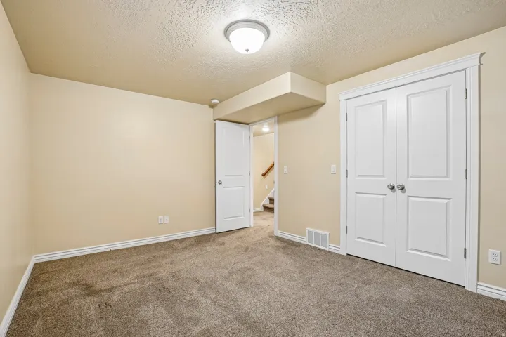 Spacious bedroom featuring neutral wall finishes, carpeted flooring, and abundant natural lighting from recessed ceiling fixtures