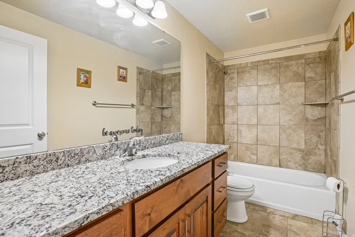 Spa-inspired primary bathroom featuring a granite-topped double vanity with wood cabinetry, dual vessel sinks, and polished chrome fixtures