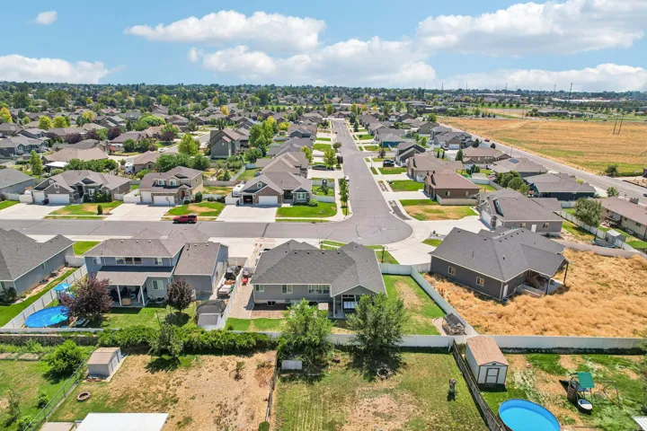 Aerial view showcasing a newly developed residential community featuring contemporary single-family homes with dark architectural rooflines, manicured lawns, and mature landscaping