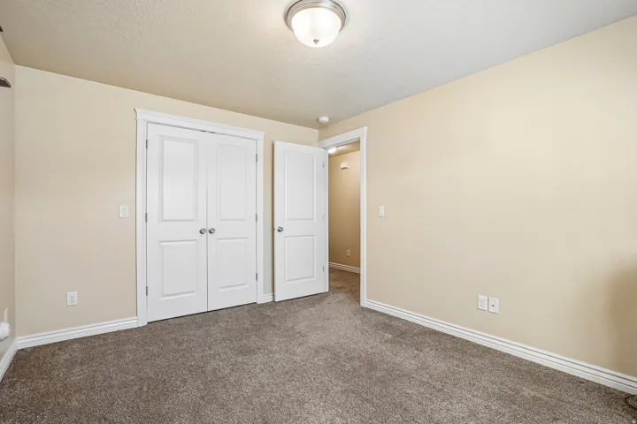 Spacious bedroom featuring neutral wall finishes, plush carpeting, and abundant natural light from recessed ceiling fixtures
