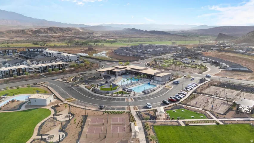 Community hub featuring a central building with an outdoor swimming pool, multiple tennis courts, and expansive green spaces