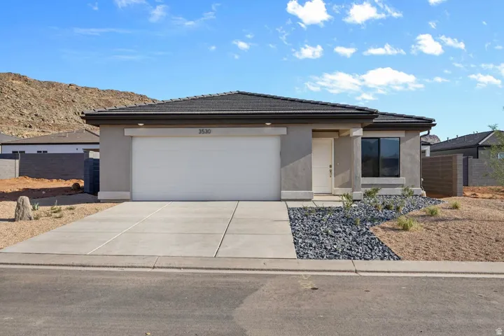 Contemporary stucco residence featuring a dark tile roof, a white garage door, and a white entry door