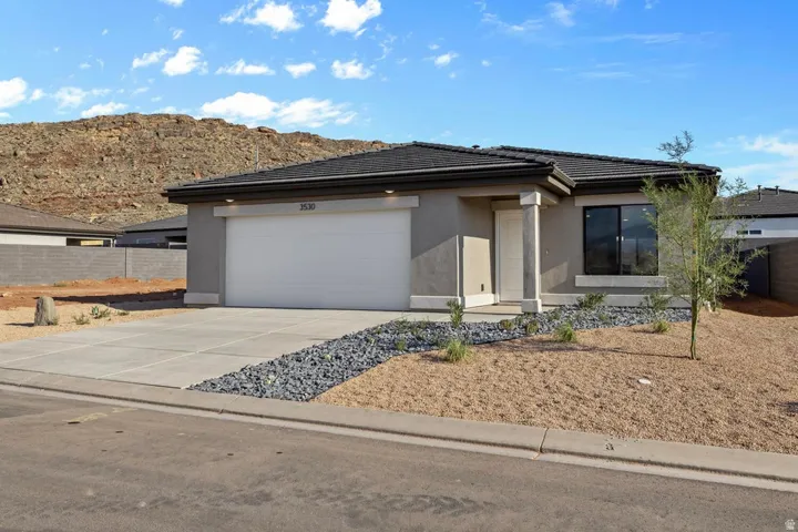 Contemporary single-story residence featuring a stucco exterior, an attached two-car garage, and a dark tile roof